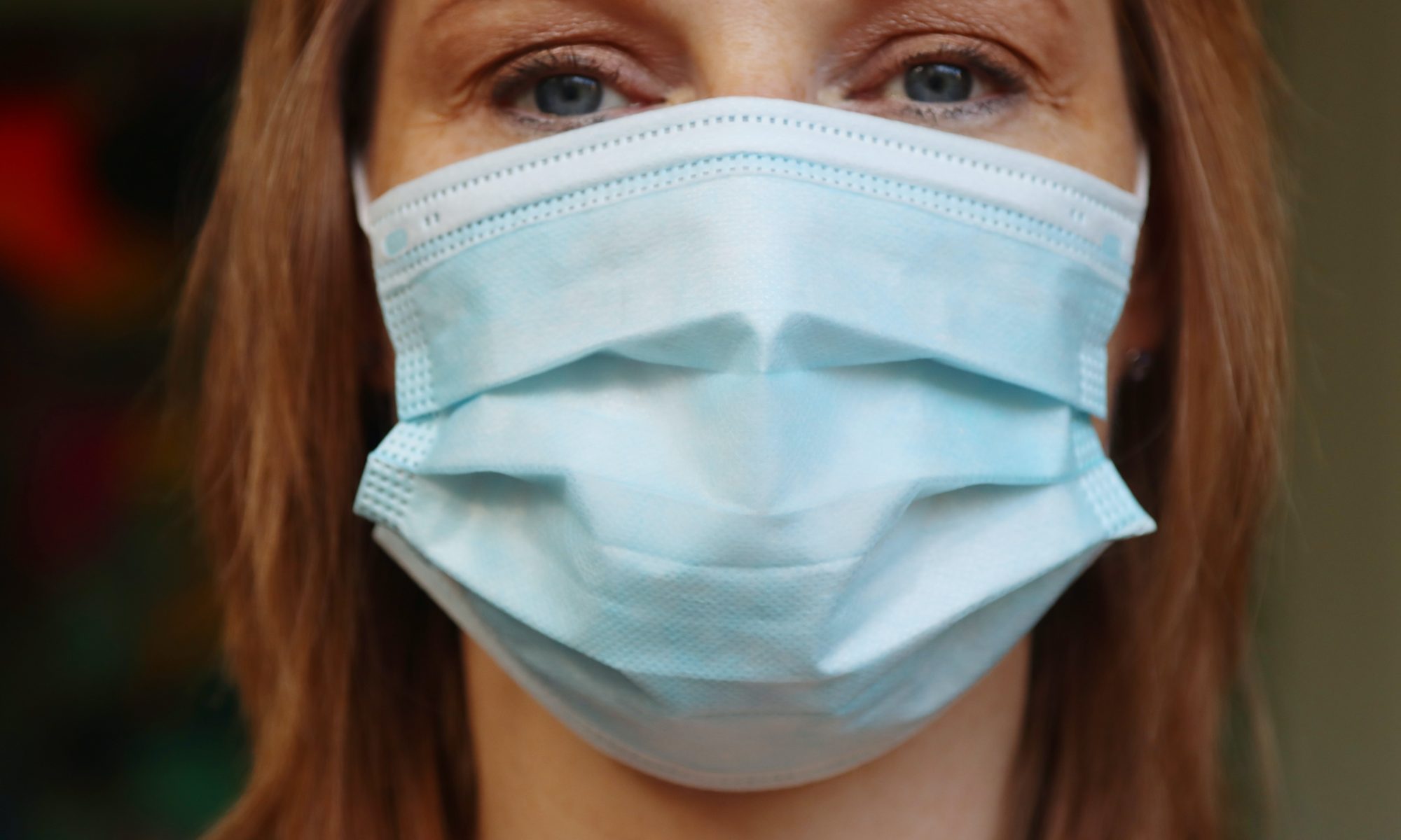Woman wearing light blue disposable face mask.