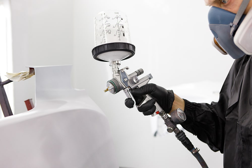 Auto paint technician sprays a car.